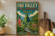 A vintage-style metal sign for the Iao Valley State Monument in Hawaii, featuring a mountainous landscape with a waterfall and tropical plants.
