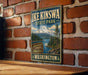 A vintage-style metal sign for Ike Kinswa State Park in Washington, featuring a mountain landscape and a river.