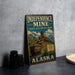 A vintage-style sign for Independence Mine, a historical park in Alaska, featuring an illustration of a mining operation and the text "Alaska Gold History".