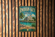 A vintage-style metal sign for Indian Key Historic State Park in Florida, featuring a tropical beach scene with palm trees and a small building.