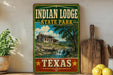 A vintage-style sign for Indian Lodge State Park in Texas, featuring a scenic landscape with a waterfall and a cabin.