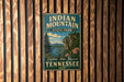 A vintage metal sign for Indian Mountain State Park in Tennessee, featuring a scenic landscape with a river, mountains, and pine trees.