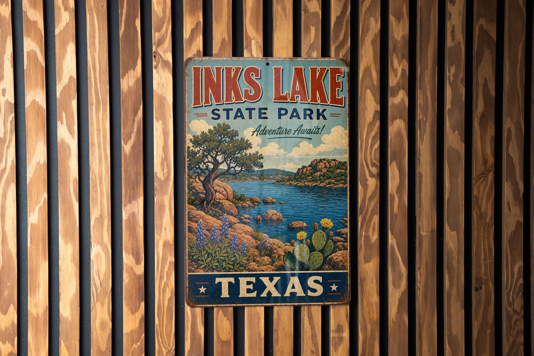 A vintage metal sign for Inks Lake State Park in Texas, featuring a scenic landscape with a lake, mountains, and cacti.