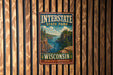 A vintage metal sign for Interstate State Park in Wisconsin, featuring a scenic landscape with a river, cliffs, and pine trees.