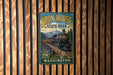 A vintage-style metal sign for Iron Horse State Park in Washington, featuring a train on a bridge and surrounded by mountains.