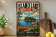 A vintage-style sign for the Island Lake Recreation Area in Michigan, featuring a red canoe and a scenic landscape with pine trees and a lake.