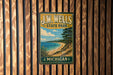 A vintage-style metal sign for JW Wells State Park in Michigan, featuring a scenic landscape with a beach, trees, and a lake.