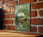 A vintage-style metal sign displaying the name "Jamaica State Park" and the location "Vermont" is mounted on a brick wall.
