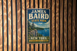 A vintage-style metal sign for James Baird State Park in New York, featuring a scenic landscape with a lake, cliffs, and a sailboat.
