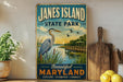 A vintage-style sign for "Jane's Island State Park" featuring a heron and a wooden pier, with the text "Beautiful Maryland" and "Explore, Discover, Connect" below.