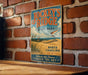 A vintage-style metal sign for Jockey's Ridge State Park in North Carolina, featuring a scenic beach landscape and a hang glider.