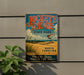 A vintage-style metal sign for Jockey's Ridge State Park in North Carolina, featuring a beach scene and a hang glider.