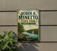 A vintage-style metal sign for John A. Minetto State Park in Connecticut, featuring a scenic landscape with a lake, trees, and a sailboat.