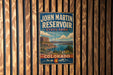 A vintage-style metal sign for John Martin Reservoir, a state park in Colorado, is displayed on a wooden wall.