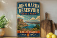 A vintage-style sign for John Martin Reservoir, a state park in Colorado, featuring a scenic landscape with mountains, water, and a lake.