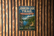 A vintage metal sign for the Johnson-Sauk Trail, located in the State Recreation Area of Illinois, is displayed on a wooden wall.