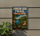 A vintage trail sign for Johnson-Sauk Trail, located in the State Recreation Area of Illinois, featuring a scenic landscape with a river and mountains.