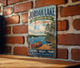 A vintage-style metal sign for Jordan Lake, North Carolina, featuring a scenic image of a lake with a canoe and a sailboat.