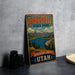 A vintage-style metal sign for Jordanelle State Park in Utah, featuring a scenic landscape with mountains, a lake, and pine trees.