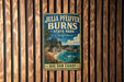 A vintage-style metal sign for Julia Pfeiffer Burns State Park in California, featuring a scenic coastal landscape with palm trees, rocky cliffs, and a body of water.