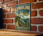 A vintage-style metal sign for the Cumberland Trail in Tennessee, featuring a scenic illustration of a mountain landscape with a winding trail.