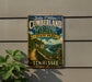 A vintage-style metal sign for the Cumberland Trail at Tennessee State Park, featuring a scenic mountain landscape and a winding trail.