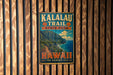 A vintage metal sign for Kalalau Trail State Park in Hawaii, featuring a scenic mountain landscape and the text "Hawaii The Garden Isle".