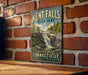 A vintage-style sign for Kent Falls State Park in Connecticut, featuring a scenic waterfall surrounded by lush greenery.
