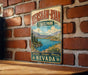 A vintage metal sign for Kershaw-Ryan State Park in Nevada, featuring a scenic landscape with mountains, a lake, and pine trees.