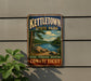 A vintage-style metal sign for kettletown state park, featuring a scenic landscape with a river, trees, and mountains.