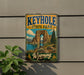 A vintage-style sign for Keyhole State Park in Wyoming, featuring a scenic landscape with a large rock formation, a lake, and a pine tree.