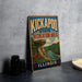 A vintage-style metal sign for the Kickapoo State Recreation Area in Illinois, featuring a scenic landscape with a rock formation and a river.