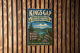 A vintage metal sign for the Kings Gap Environmental Education Center in Pennsylvania, featuring a scenic landscape with a bird perched on a rock.