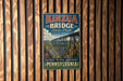 A vintage-style metal sign for Kinzua Bridge State Park in Pennsylvania, featuring a scenic image of the bridge and surrounding landscape.
