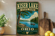 A vintage-style sign for Kiser Lake State Park in Ohio, featuring a scenic illustration of a lake with a canoe and trees, along with the text "Kiser Lake State Park" and "OHIO" prominently displayed.