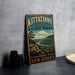 A vintage metal sign for Kittatinny Valley State Park, featuring a scenic landscape with a river and mountains, is displayed on a gray countertop next to some black camera lenses.