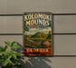 A vintage metal sign for Kolomaki Mounds State Park in Georgia, featuring a scenic landscape with a hill, a river, and a vase.