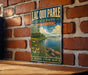 A vintage-style metal sign for Lacquis Parle State Park in Minnesota, featuring a scenic landscape with a lake, mountains, and flowers.