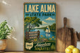 A vintage-style sign for Lake Alma State Park, featuring a scenic illustration of a lake, trees, and a sailboat, along with the text "BOATING FISHING HIKING" and "Adventure Awaits!"