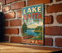 A vintage-style metal sign for Lake Anita State Park in Iowa, featuring a scenic illustration of a lake, canoe, and surrounding landscape.