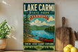 A vintage-style sign for Lake Carmi State Park in Vermont, featuring a scenic image of a lake, mountains, and a red canoe.