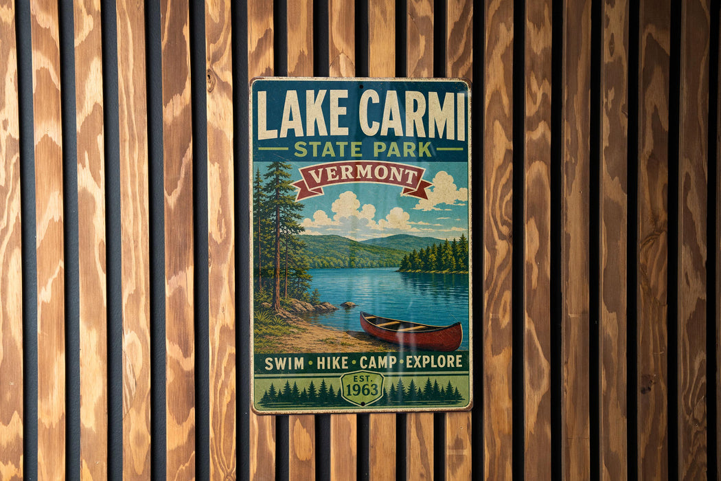 A vintage-style metal sign for Lake Carmi State Park in Vermont, featuring a scenic image of a lake, mountains, and a canoe.