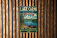 A vintage-style metal sign for Lake Carmi State Park in Vermont, featuring a scenic image of a lake, mountains, and a canoe.