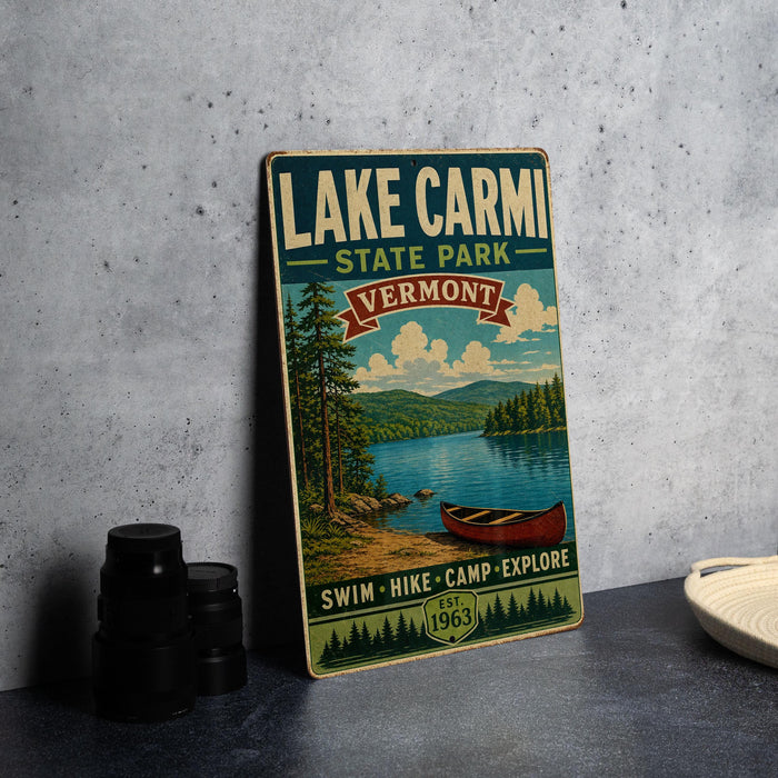 A vintage-style metal sign for Lake Carmi State Park in Vermont, featuring a scenic illustration of a lake, mountains, and a canoe.