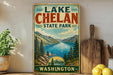 A vintage-style sign for Lake Chelan State Park in Washington, featuring a scenic mountain landscape with a lake and pine trees.