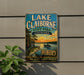 A vintage-style sign for Lake Claiborne State Park in Louisiana, featuring a scenic illustration of a lake, palm trees, and a sunset.