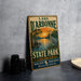 A vintage-style sign for Lake D'Arbonne State Park in Louisiana, featuring an illustration of a bird and a sunset over a body of water.