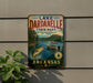 A vintage-style sign for Lakeardelle State Park in Arkansas, featuring a scenic image of a lake with a fish leaping out of the water and a boat on the water.