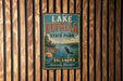A vintage-style metal sign for Lake Eufaula State Park in Oklahoma, featuring a scenic landscape with a lake, mountains, and a bald eagle.