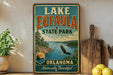 A vintage-style sign for Lake Eufaula State Park in Oklahoma, featuring a scenic landscape with a lake, mountains, and an eagle in flight.